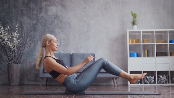 Young and sporty girl in sportswear is doing exercises in home interior.