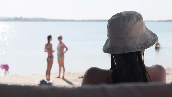 Relax on the Beach. View From the Back on Woman in a Hat Lying on the Shore