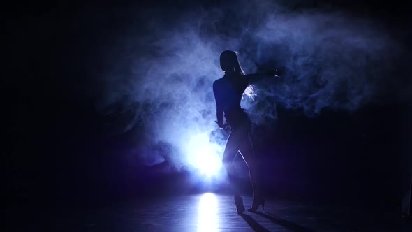 Dancing Girl in Latin Style in Studio, Silhouette. Dark Background