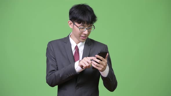 Young Happy Asian Businessman Using Phone and Getting Good News