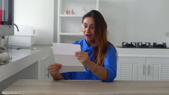 Attractive Woman in Blue Shirt Sit on Kitchen Hold in Hands Sheets Read Great News in Letter Feels