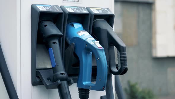 A Man Is Putting an Electric Refueling Nozzle Back Into Its Place