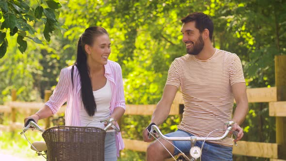 Happy Couple with Bicycles Talking at Summer Park