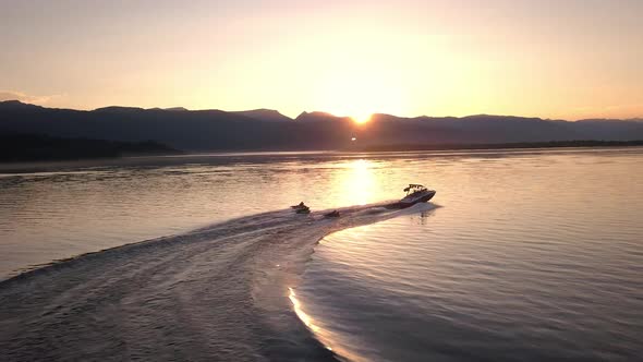 Aerial view following boat pulling people on tubes