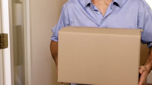 Smiling man carrying boxes in new house