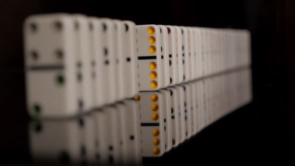 Businessman Hand Stopping Dominoes Row From Falling on a Black Background