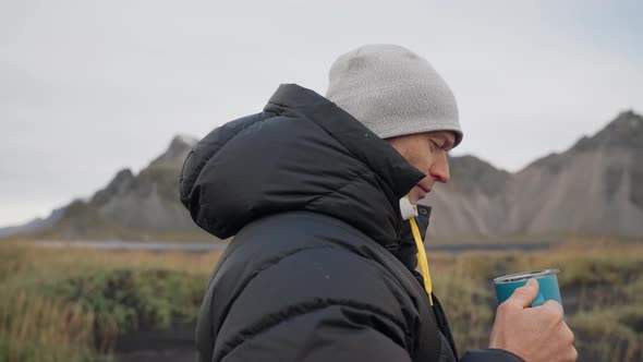 Man Drinking Coffee On Black Beach Near Vestrahorn Mountain