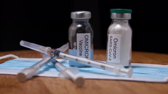 Medical mask, syringes and vials with Omicron vaccine on wooden background