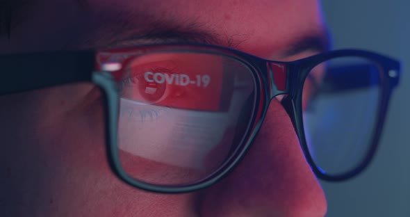 Closeup Portrait of Reflection in Eyeglasses Coronavirus Warning Man Using Laptop Reading News About