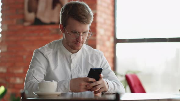 Problematic Internet Use By Modern Smartphone Adult Man is Sitting in Cafe Alone and Chatting in