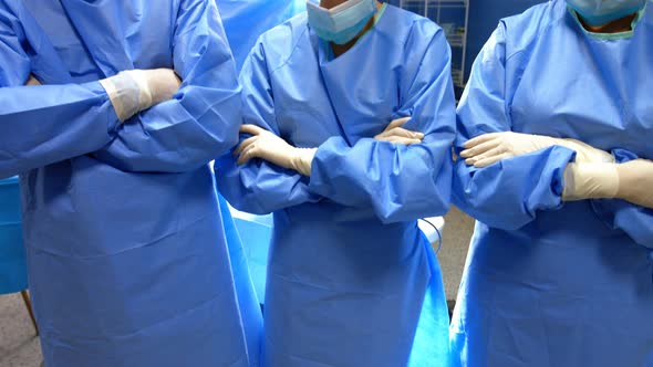 Portrait of surgeon and nurses standing with arms crossed in operation room