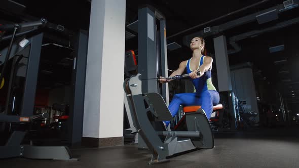 Pretty Girl Bodybuilder Training Hands on Weight-Lifting Training Machine in Gym