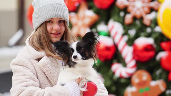 Beautiful Girl with Dog Papillon in Her Arms on Winter Christmas Streets