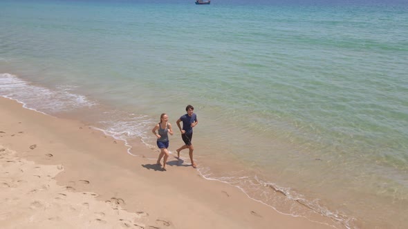 Aerial Shot of a Young Man and Woman Jogging on a Beautiful Beach. Concept of Healthy Lifestyle and