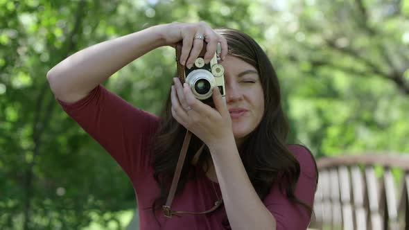 Young woman winding film on camera to take vertical photo