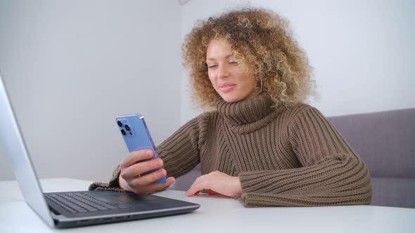 Happy young female using modern smartphone at home. Freelancer woman communicating online in 4k