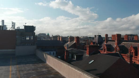 Forwards Low Flight From Parking Lot Above Roofs of Historical Brick Houses with Many Chimneys