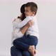Beautiful Happy Smiling Loving Woman Sitting on White Background and Hugging Her Child Which Running - VideoHive Item for Sale