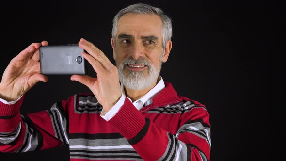 An Elderly Man Takes Pictures with a Smartphone - Black Screen Studio