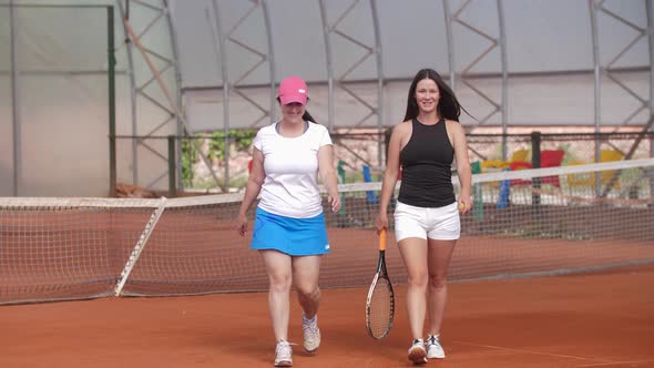 Two Adult Women Walking on the Tennis Court