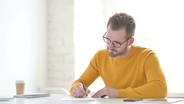 Man Writing on Paper in Office