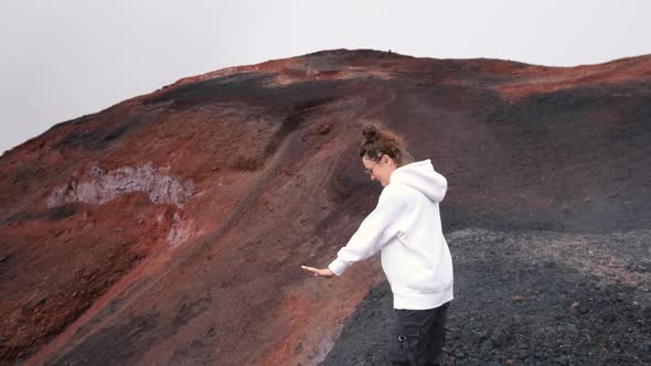 A Young Tourist Girl on the Top of the Tolbachik Volcano Warms Her Hands with a Ferry From the