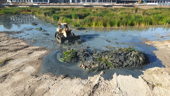 Aerial View Large Bulldozer Cleans the Bottom of the Lake From Thickets and Swamps