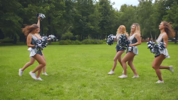 Group of Excited Cheerleading Girls Shaking Pompons Smiling at Camera