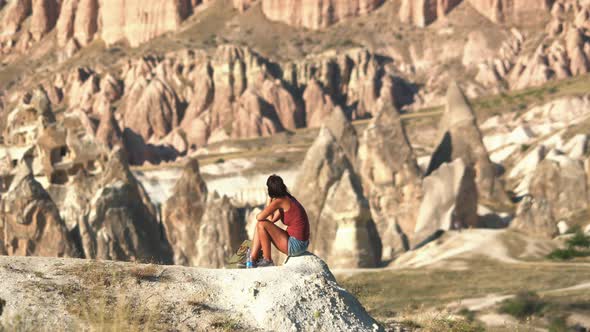 Woman Sitting by the Scenic View of Stunning Red Sandstone Hoodoos