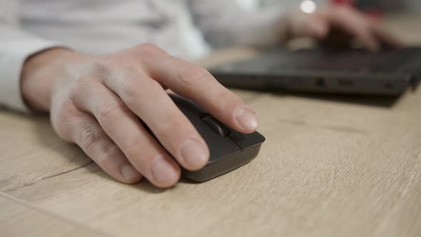 Caucasian male use wireless black mouse on wooden table for computer work