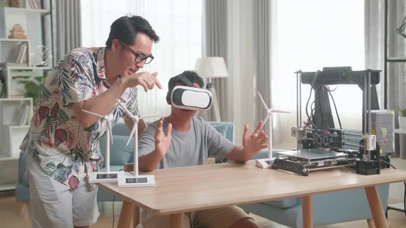 Asian Father Teach His Son While Wearing Vr Glasses With Electric Wind Turbine Model And 3D Printer