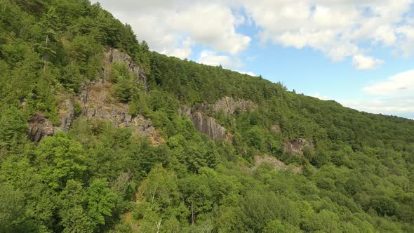 Stunning one minute long aerial shot of drone flying up over forest and cliffs