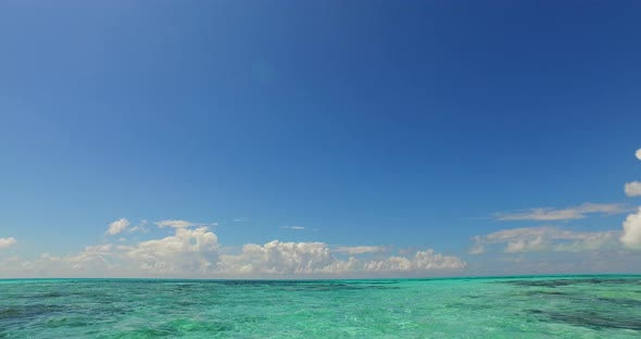 Daytime fly over copy space shot of a white paradise beach and blue water background in vibrant 4K