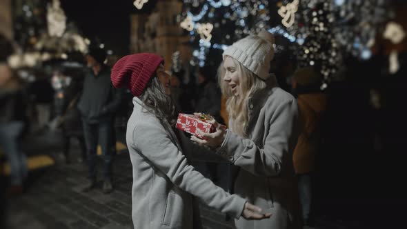 Two Friends Presenting Gifts to Each Other at Xmas Night at Old Town Square