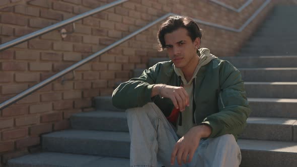 Handsome Young Man with Piercing in Ear Sitting on Stairs