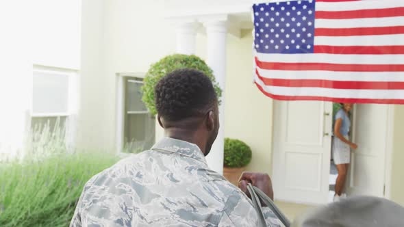 African american male soldier embracing his smiling wife over american flag