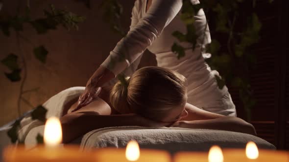 Young, healthy and beautiful woman gets massage therapy in the spa salon.