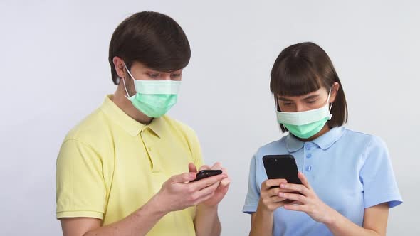 Young Couple Scrolling Smartpones in Protection Mask and Surprised From News About Coronavirus