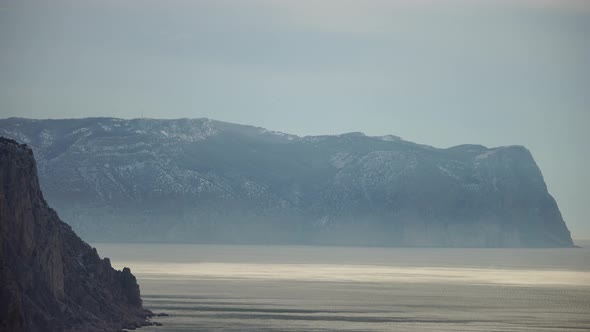 Snow Covered Rocky Cliffs Over Sea