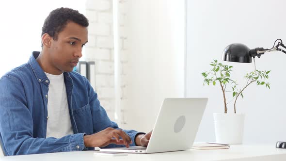 Afro-American Man Typing On Laptop in Office