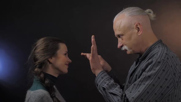 Elderly Man and Woman with Braid Imitate Pantomime Moves