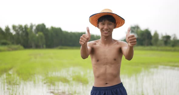 Young farmer topless standing and arms folded in rice field