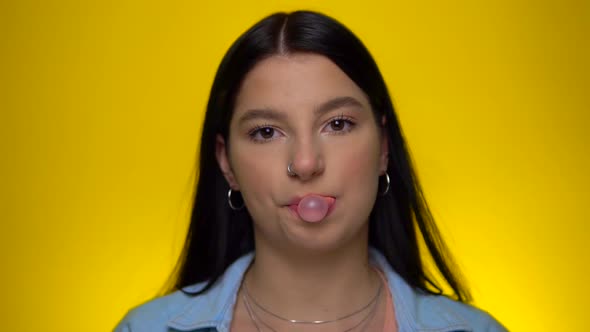 Woman with Piercing Nose Looking at Camera and Blowing Bubble Gum in Slow Motion