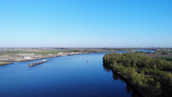 Freight Barge Sailing At Oude Maas River Near Puttershoek, South Holland, Netherlands. - aerial