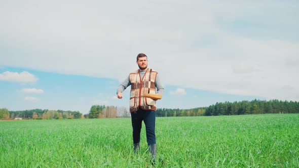 A Young Peasant Man Is Sowing the Field with Grain at a Village. A Farm Concept.