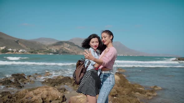 Two Girls Making Selfie on Cliff Over Sea