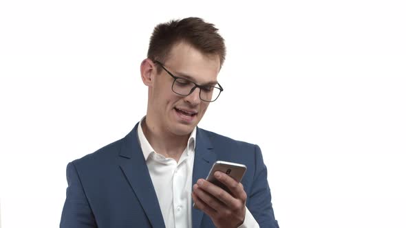 Handsome Businessman in Glasses and Blue Suit Looking Thoughtful at Mobile Phone While Scrolling