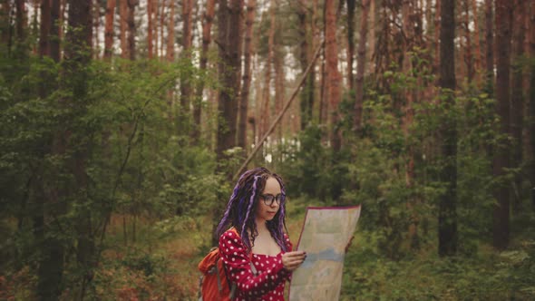 Traveling Woman with Dreadlocks with Map in Woods