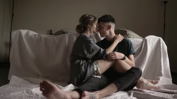 Young Beautiful Lovely Couple Is Having a Romantic Time. Sitting on the Floor By the Bed Embracing