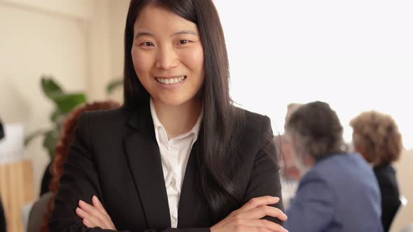 Asian Woman Smiling on Camera While Working with Colleagues Inside Bank Office